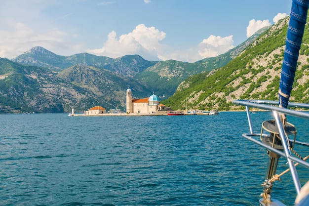 The yacht sails near the picturesque Gospa od Skrpela Island in the Boka Kotorsky Bay