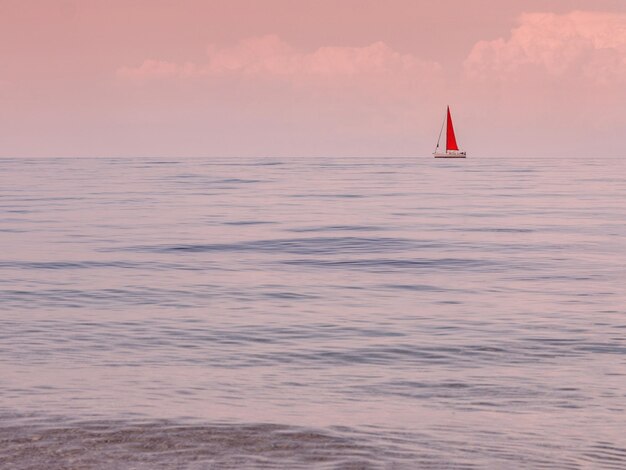 Yacht with a scarlet red sail at sunset on the island of Kefalonia in the Ionian Sea in Greece