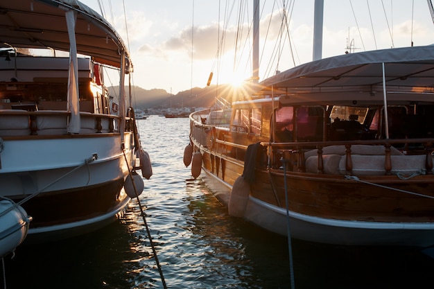 Yachts on the pier against the backdrop of a beautiful sunset sky with sunbeams