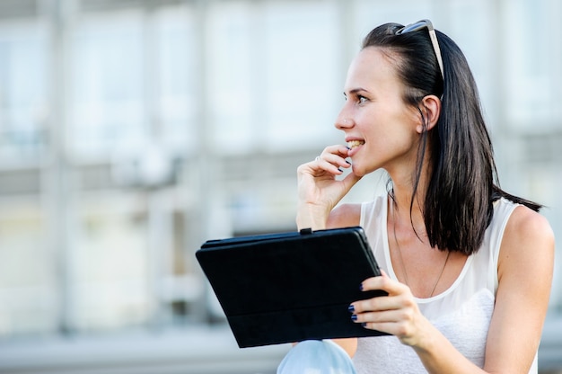 Yang and beautiful modern business woman poses outdoor with tablet computer