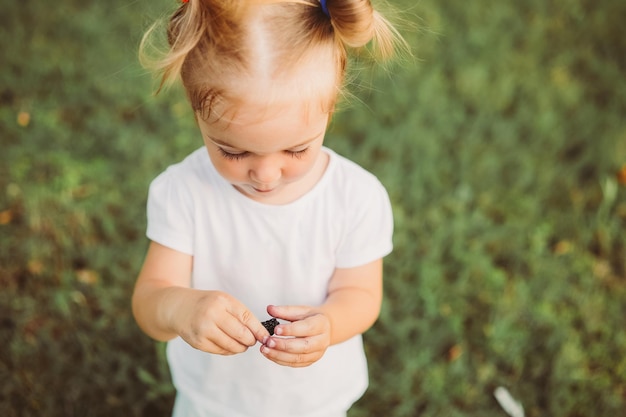 Photo year old toddler girl eating ripe black mulberries