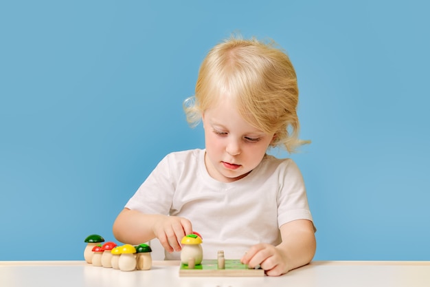 A yearold child is playing at a table with a colorful education toy on blue background