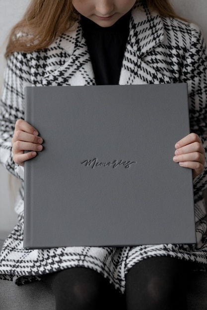 A yearold girl is sitting holding a gray leather photo book