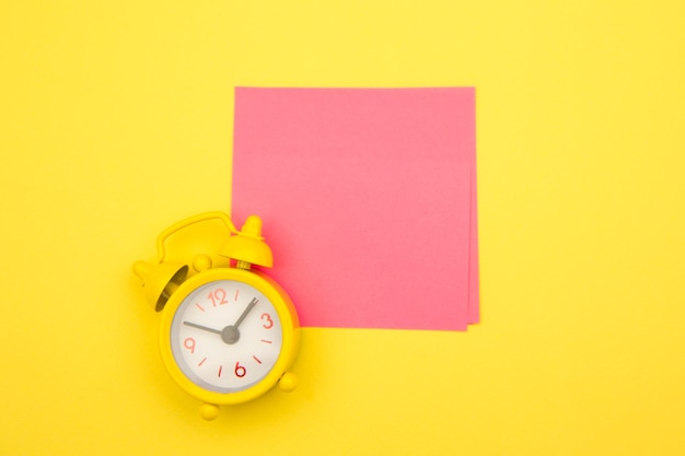 Photo yellow alarm clock and colorful sticky notes on a yellow.