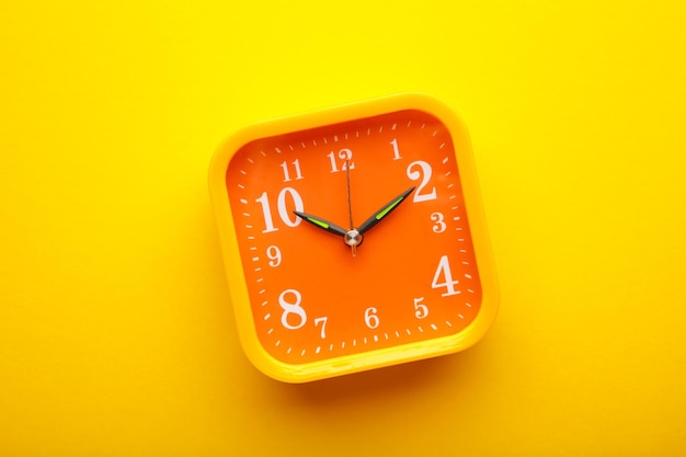 Yellow alarm clock on yellow background with copy space