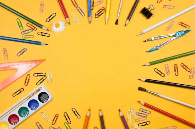 On a yellow background at the edges of the image are school supplies