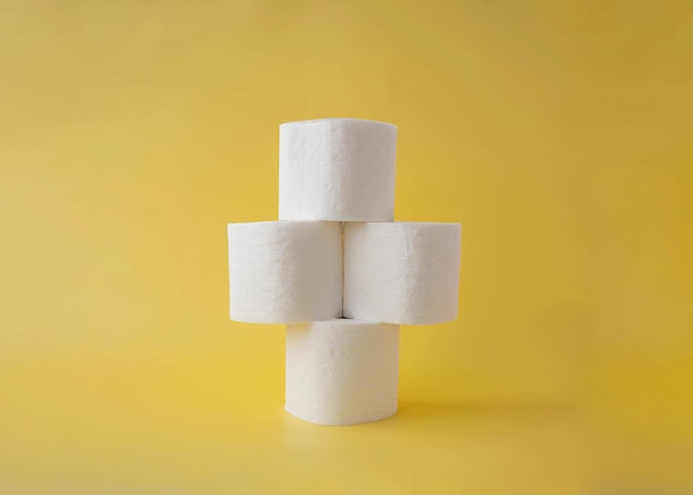 On a yellow background four rolls of toilet paper stand on top of each other