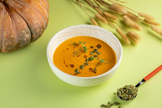 Yellow background and sweet pumpkin white bowl with food Male hand taking wooden spoon