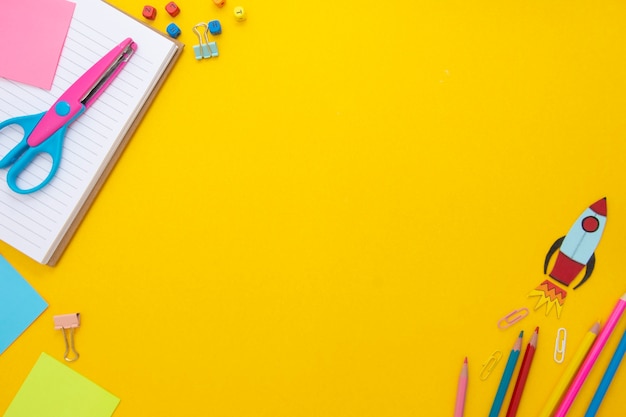 Yellow background with a notebook and school supplies