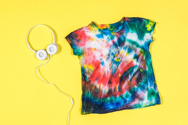 Yellow background with tie dye tshirt and headphones Flat lay