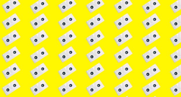 A yellow background with white objects on the top and a black dot on the bottom.