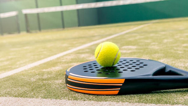 Yellow ball over padel tennis racket in green court outdoors with natural light