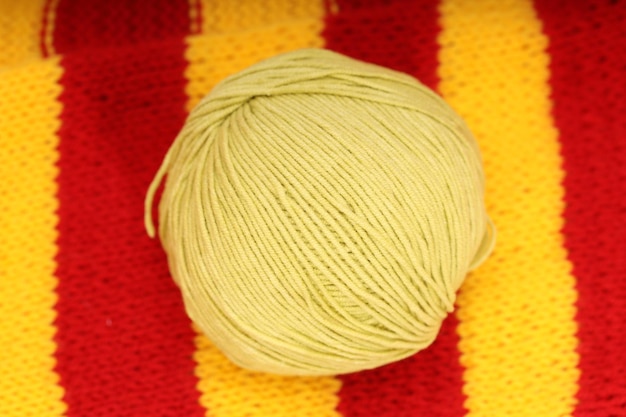 A yellow ball of wool lies on a knitted napkin. High quality photo