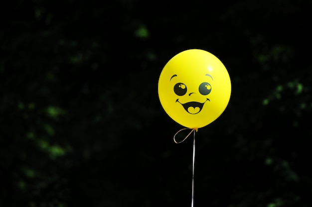 Yellow balloon on a string with a painted face