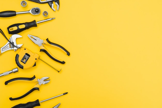 Yellow and black handy tools (pilers and screwdriver) isolated on yellow background