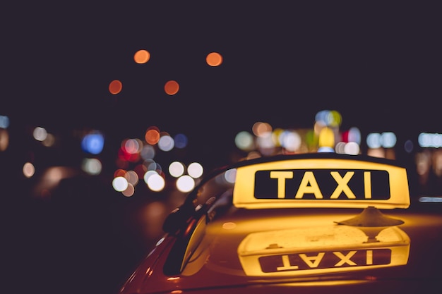 Yellow and black sign of a taxi put on a car at night