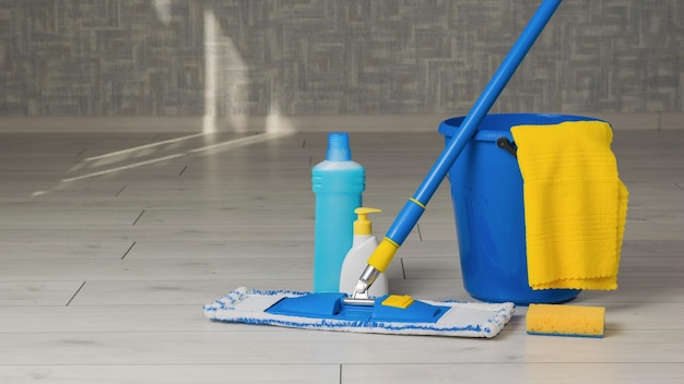 Yellow and blue cleaning kit in the room on the wooden floor Home and office cleaning kit The concept of maintaining cleanliness Flat lay