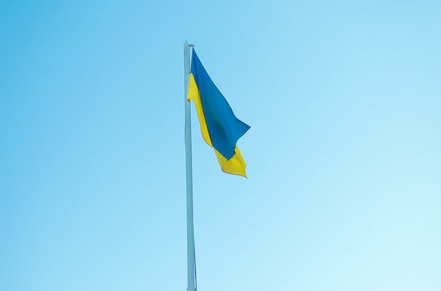 Yellow-blue flag of Ukraine on a pole against the blue sky. The official flag of the Ukrainian state