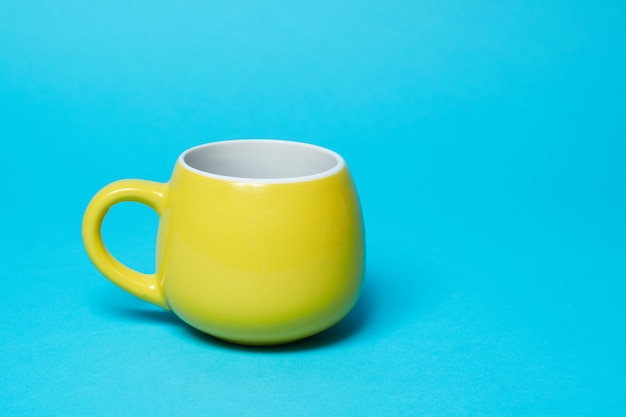 Yellow bright cup isolated on a blue wall.copy space and Simplicity