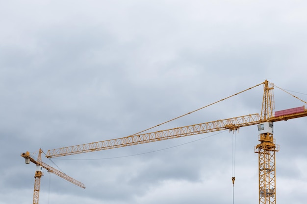 Yellow building constraction cranes against the grey sky