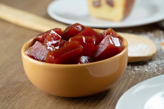 Yellow can with guava jam cut into cubes with guavas in the background on wooden table