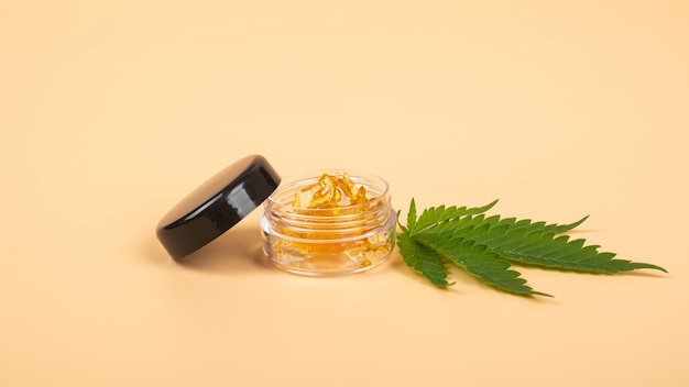 Yellow cannabis wax resin and green leaf on yellow background