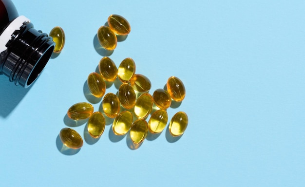 Yellow capsules with fish oil on a blue background top view