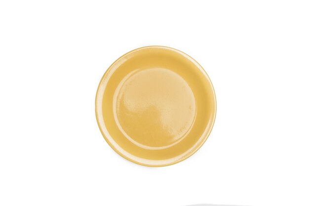 A yellow ceramic round dish on a white background with copy space in a top view