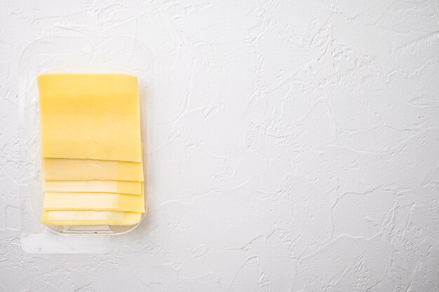 Yellow cheese slices of cheddar set, in plastic pack, on white stone