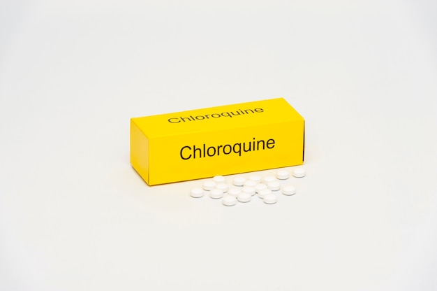 Yellow chloroquine box with scattered pills isolated on white background