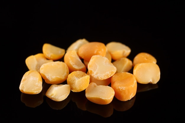 Yellow chopped peas on a black surface close up