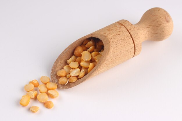 Yellow chopped peas and scoops on a white surface