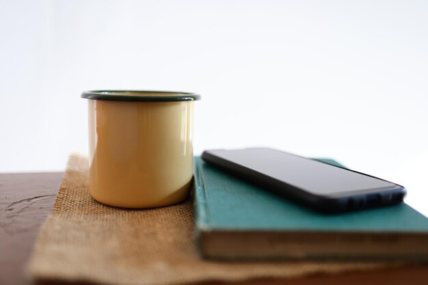 Yellow coffee mugs, phones and books on the wooden table inside the house.