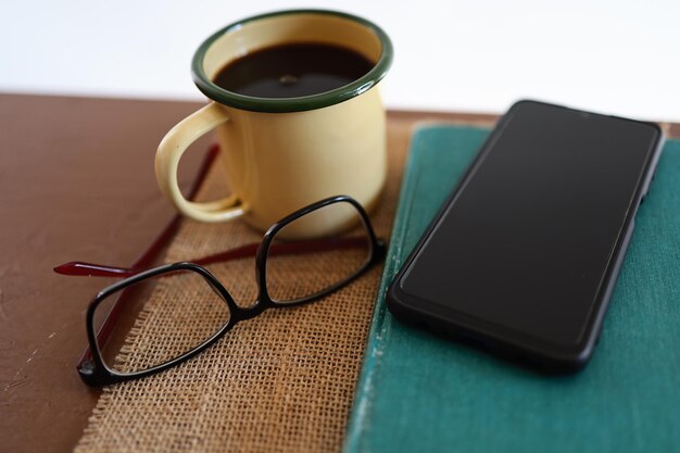 Yellow coffee mugs, phones and books on the wooden table inside the house.