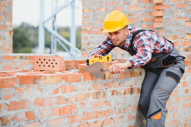 Yellow colored hard hat Young man working in uniform at construction at daytime