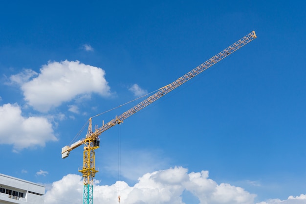 Yellow construction tower crane against blue sky