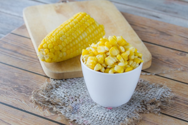 Yellow corn grain in cup on wooden table,