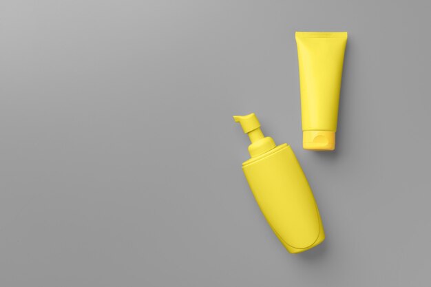 Yellow cosmetic container on gray background top view flat lay