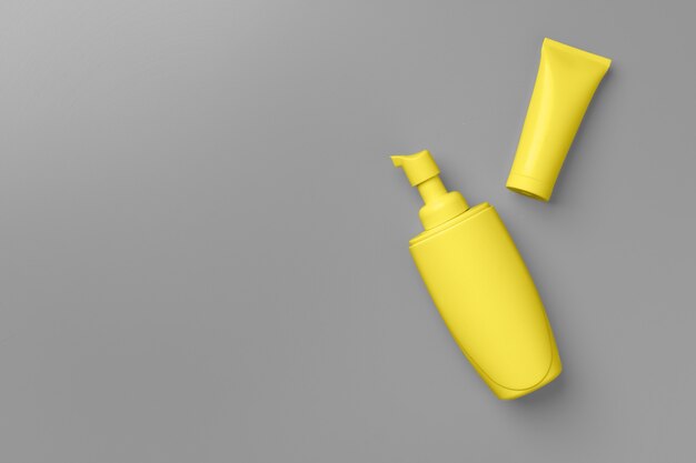 Yellow cosmetic container on gray top view flat lay