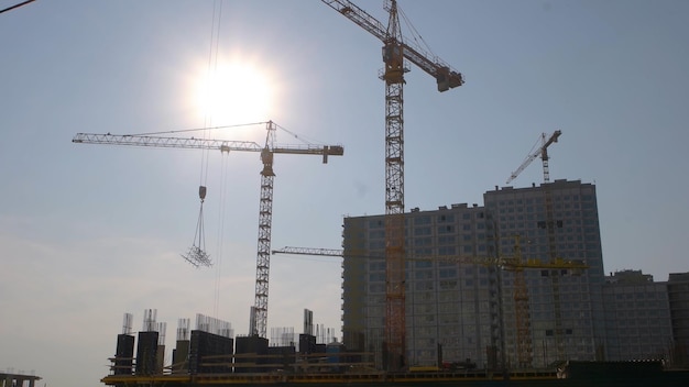 Yellow crane carrying a metal frame on the construction blue sky with a brigh sun fast speed motion