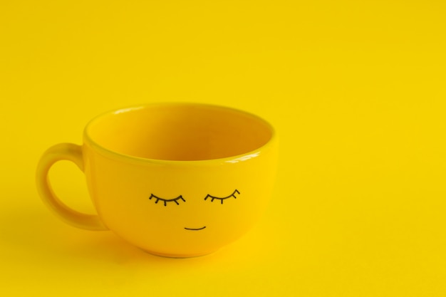 Yellow cup with cute smile face on yellow 