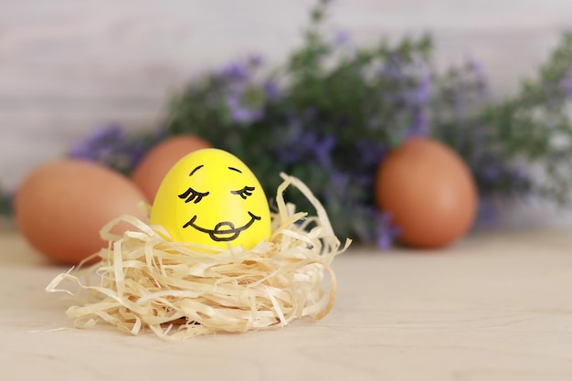 A yellow Easter egg. Egg in a nest on a wooden table