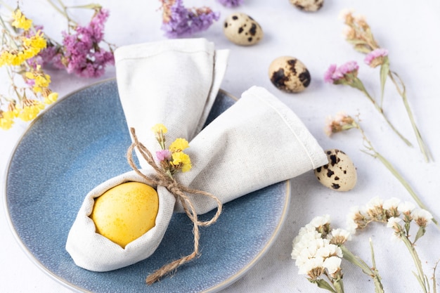 Yellow easter egg inside a napkin and beautiful table decoration