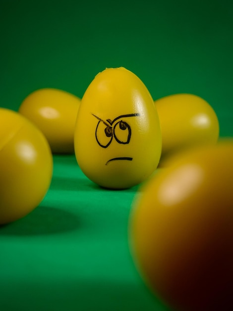 A yellow egg with an angry face is surrounded by other yellow eggs.