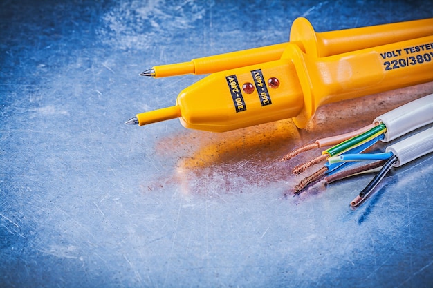 Yellow electrical tester wires on metallic background electricity concept