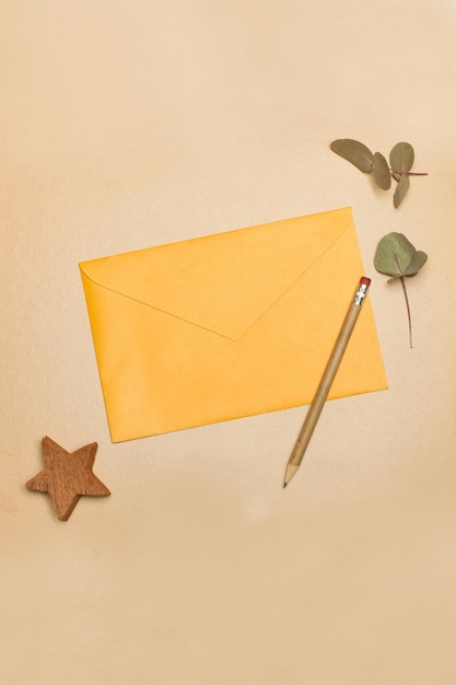 Yellow envelope and a pencil on a brown background in a top view