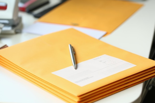 Yellow envelope with business correspondence with pen on desktop in office