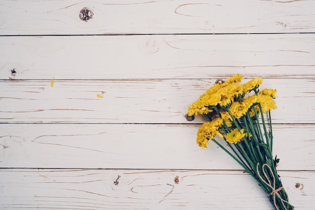 Yellow flowers of bouquet, top view on white wooden background texture with copy space