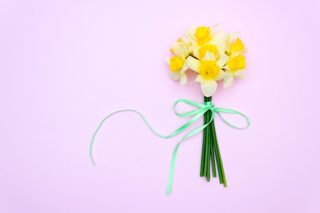 Yellow flowers on pink background. Bouquet daffodils, spring gift concept.