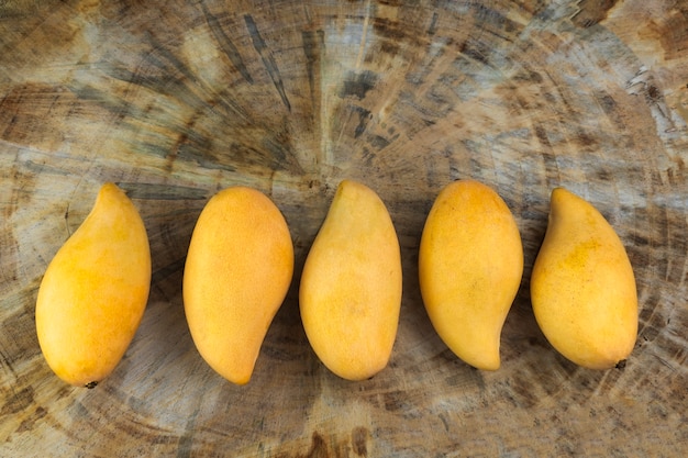 Yellow Fresh mangos on real wood table. Mango tropical fruit.